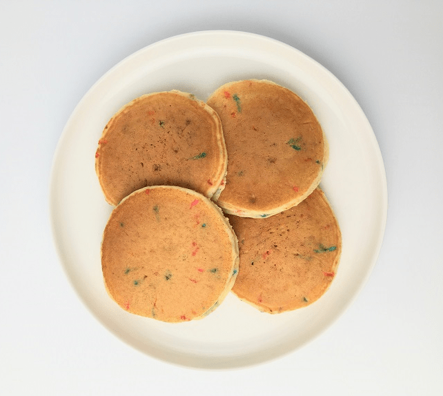 Four birthday funfetti pancakes arrange around a white plate