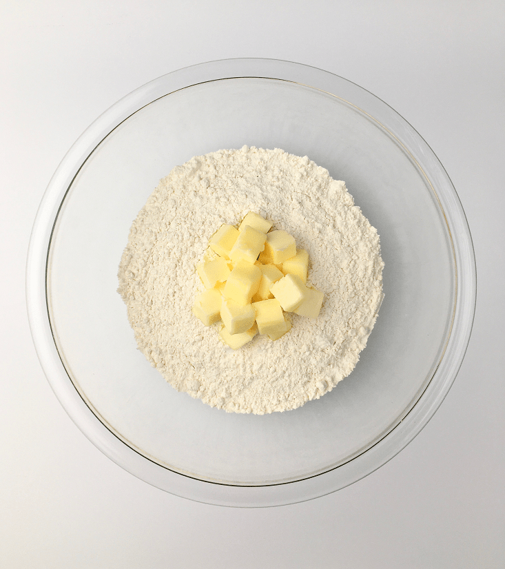 Glass bowl with dry flour mixture and cubes of cold butter