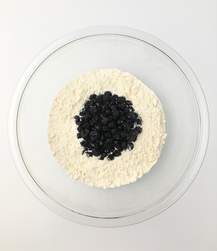 Glass bowl with butter mixed into dry flour mixture and blueberries added