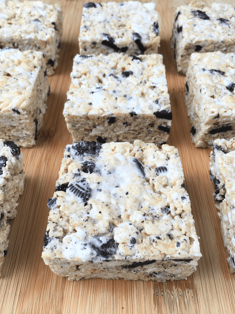 Rows of cookies and cream rice krispies treats on a wooden cutting board