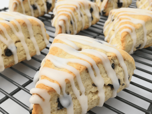 Lemon blueberry scones baked to golden brown on a cooling rack and drizzled with lemon glaze