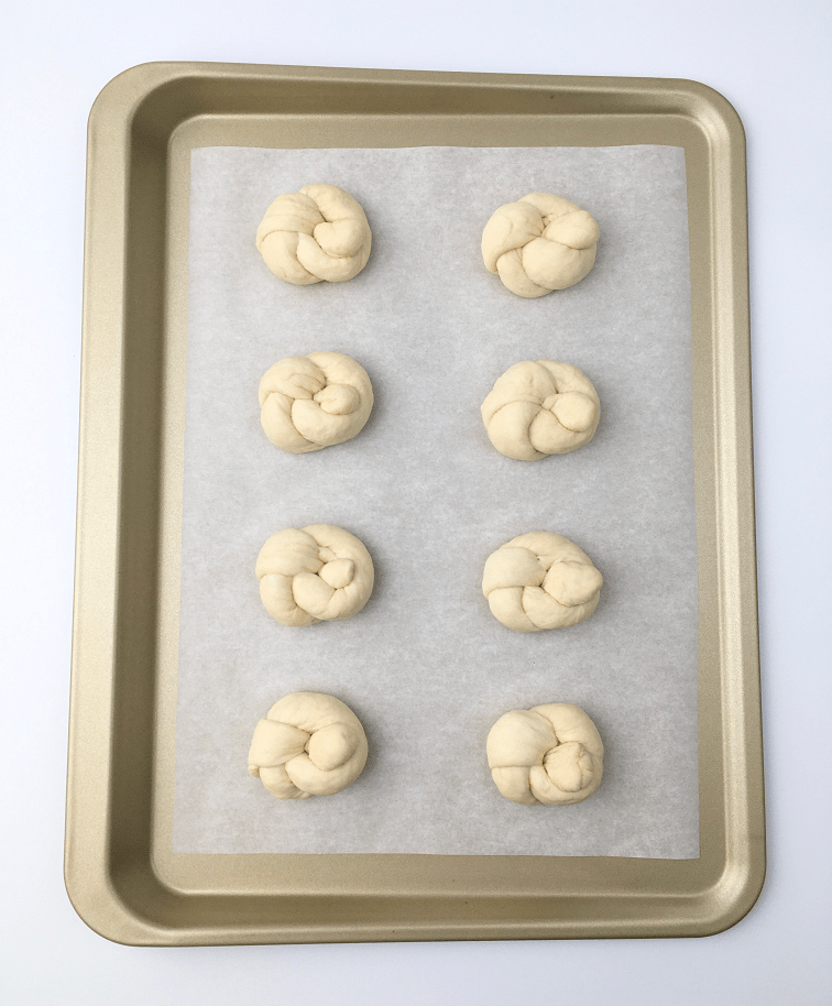 Pizza dough ropes that have been shaped into knots on a baking sheet