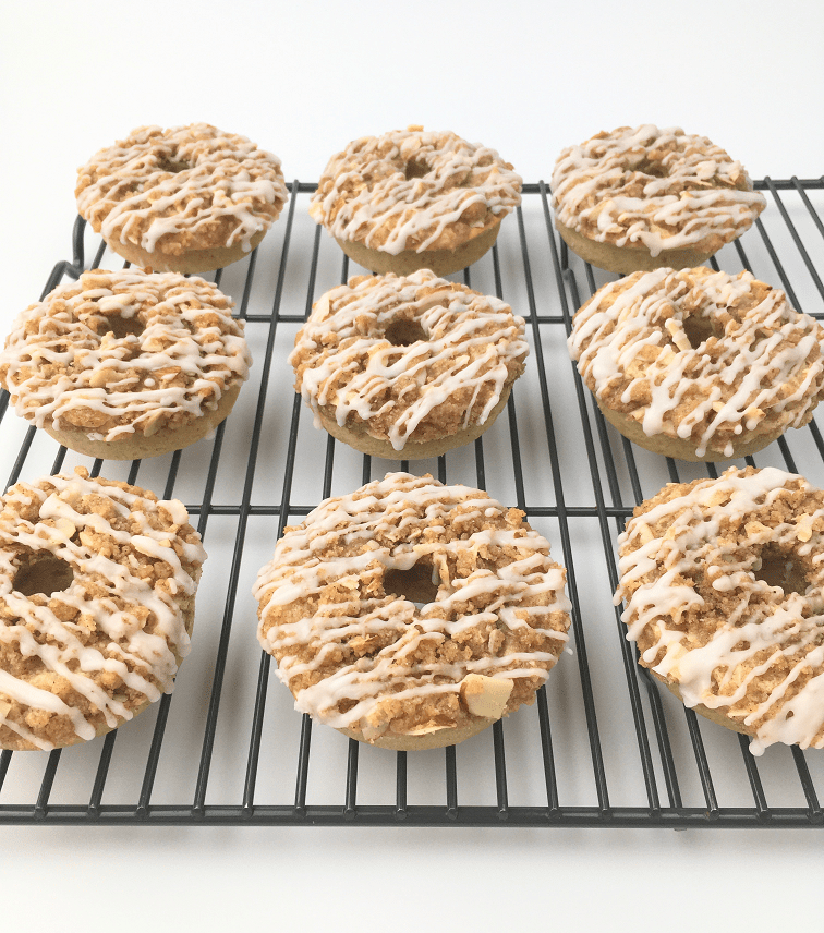 Crumb cake donuts drizzled with icing on a cooling rack