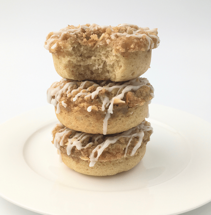 Three crumb cake donuts stacked on a white plate