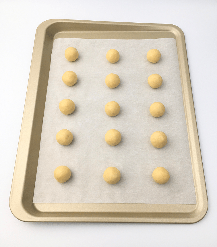 Balls of lemon sunshine cookie dough on a baking sheet