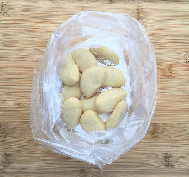 Baked lemon sunshine cookies in a plastic bag with powdered sugar