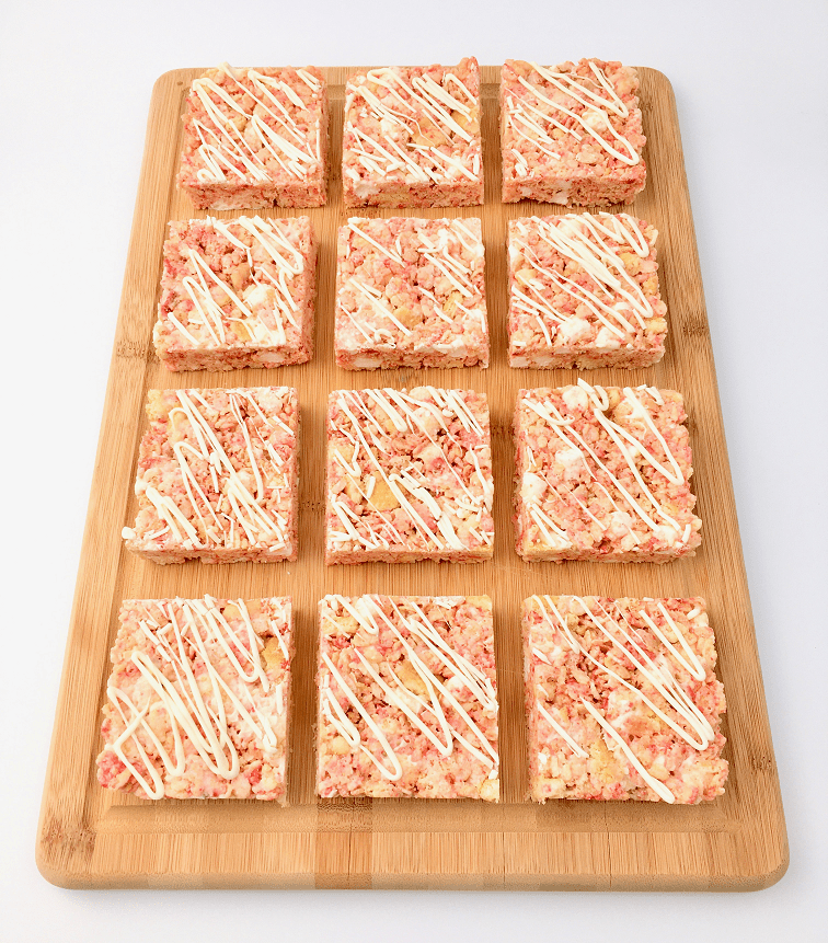 Rows of Strawberry Shortcake Rice Krispies treats on a wooden cutting board