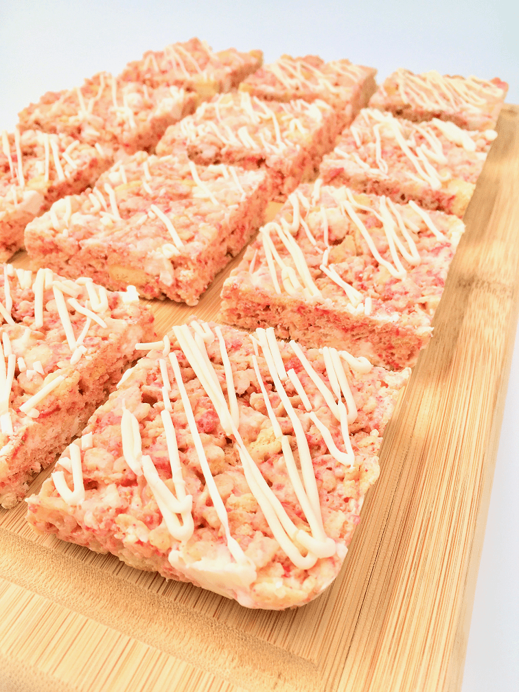 Side view of Strawberry Shortcake Rice Krispies treats on a wooden cutting board