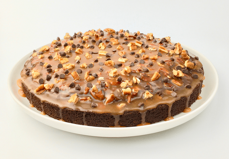 Finished brownie cake topped with caramel, pecans, and mini chocolate chips