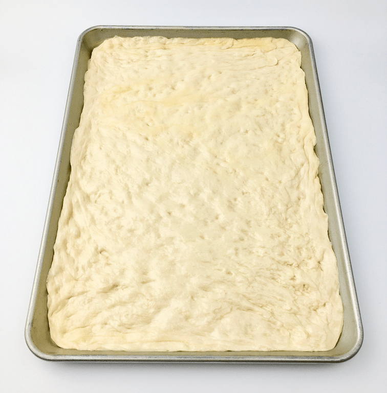 Dough for tomato pie pressed into a baking pan