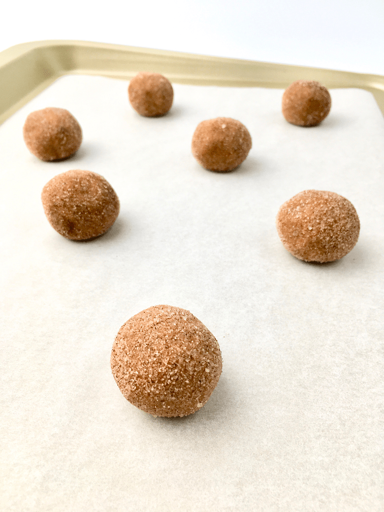 Cinnamon sugar-coated cookie dough balls on baking pan