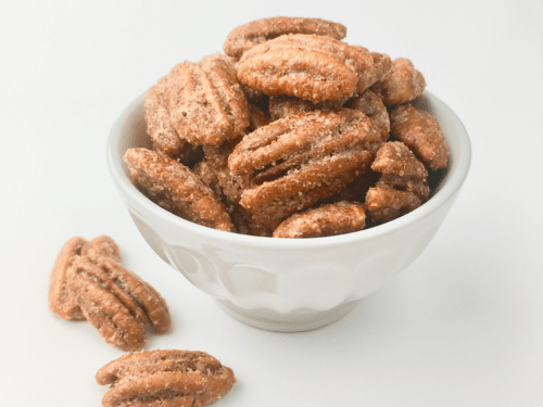 Praline pecans piled up in a white bowl