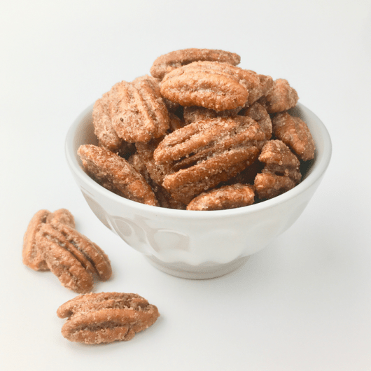 Praline pecans piled up in a white bowl