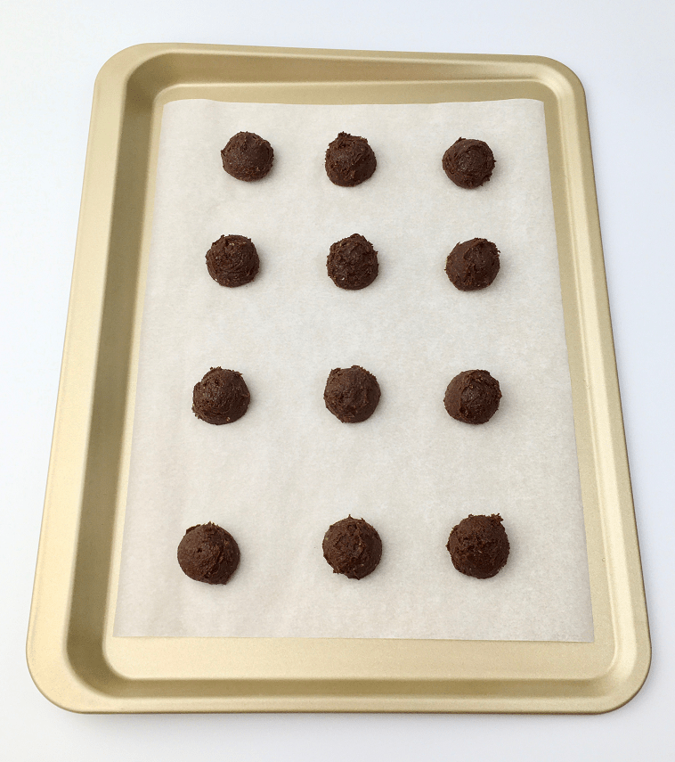 Buckeye cookie dough scooped onto a parchment-lined baking pan.