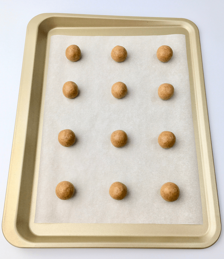 Gingerbread hug cookie dough balls on a parchment lined baking pan