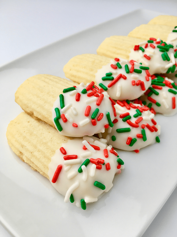 A row of stacked Italian butter cookies dipped in white chocolate and topped with red and green sprinkles