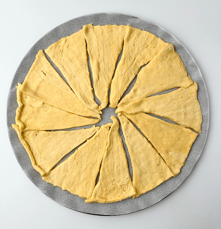 Crescent dough triangles arrange in a circle on a pizza pan