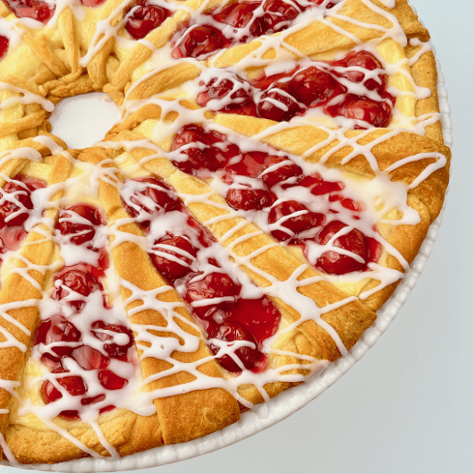 Finished cherry cream cheese crescent ring on a white plate