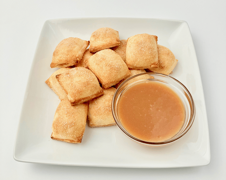 Apple pie bites on a plate with caramel dipping sauce.