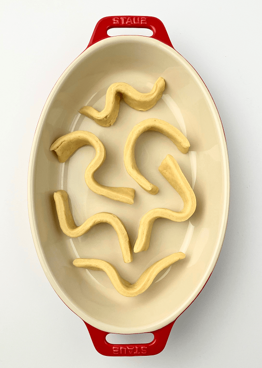 Strips of cobbler dough arranged in a red casserole dish