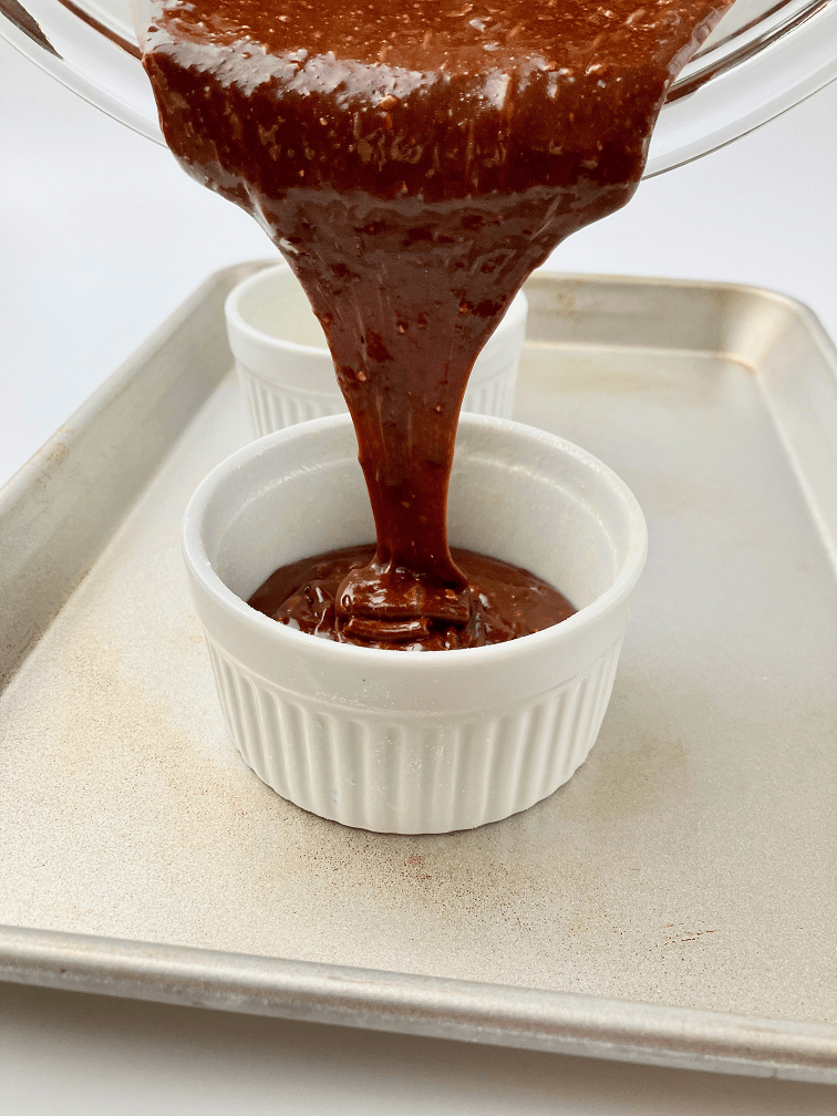 Chocolate orange lava cake batter poured into ramekin on baking pan.