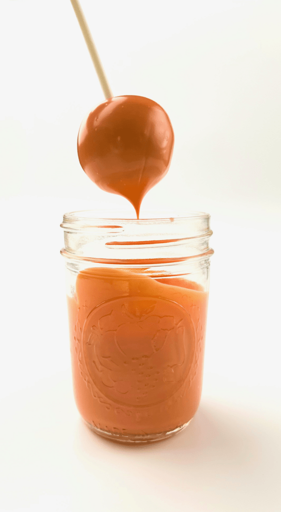 Pumpkin cake pop dipped in candy coating.