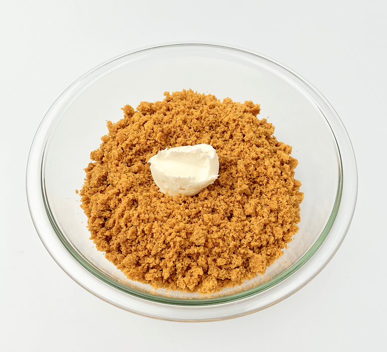 Pumpkin cake crumbs and frosting in a glass bowl.