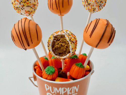 Arranged pumpkin cake pops with a bite.