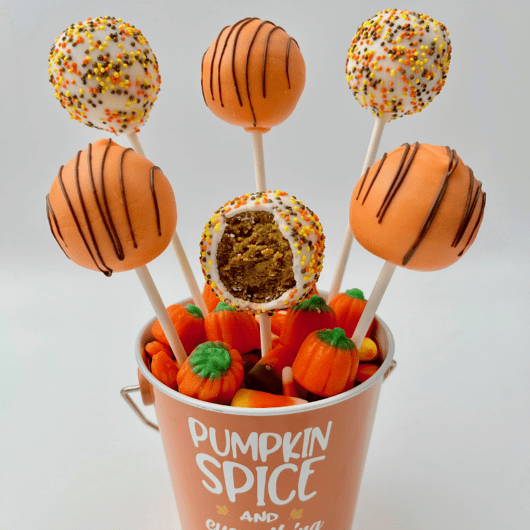 Arranged pumpkin cake pops with a bite.