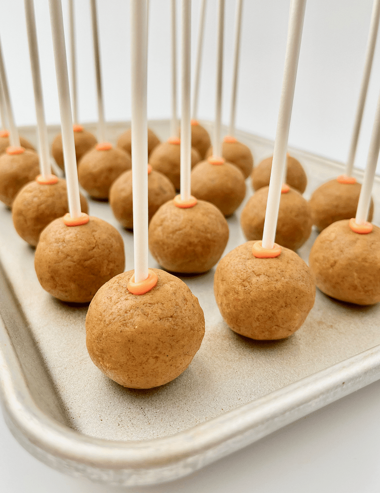 Rolled pumpkin cake pops with a lollipop stick.