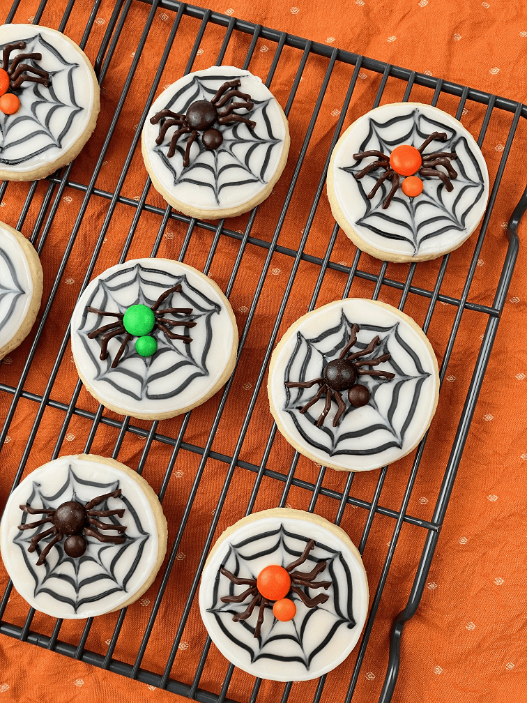 Several finished spider web cookies on a wire rack.