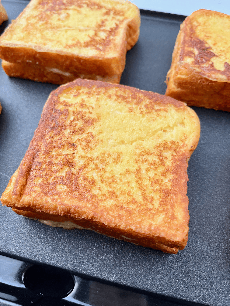 Bananas foster stuffed French toast cooking on a griddle.