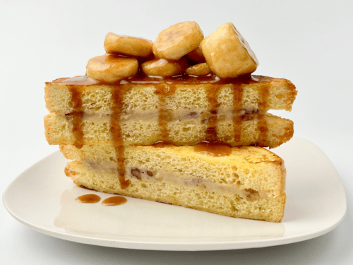 Bananas foster stuffed French toast on a white plate.