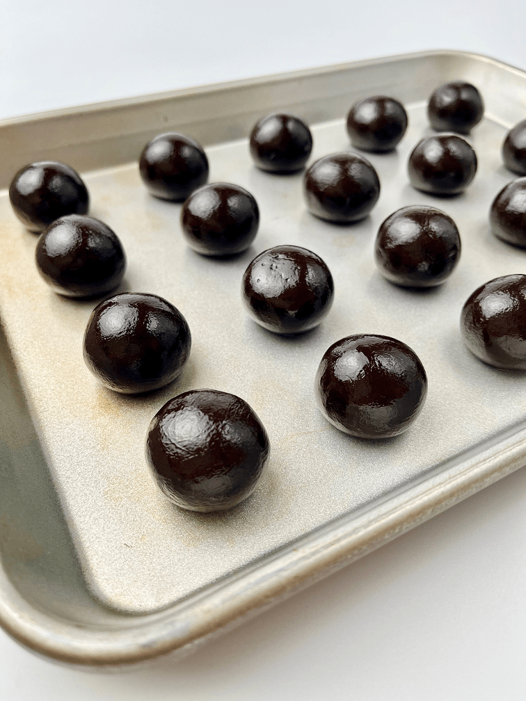 Boozy Oreo truffle dough rolled into balls on a baking pan.