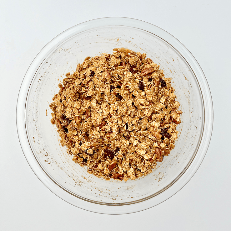 Gingerbread granola ingredients mixed in a glass bowl.