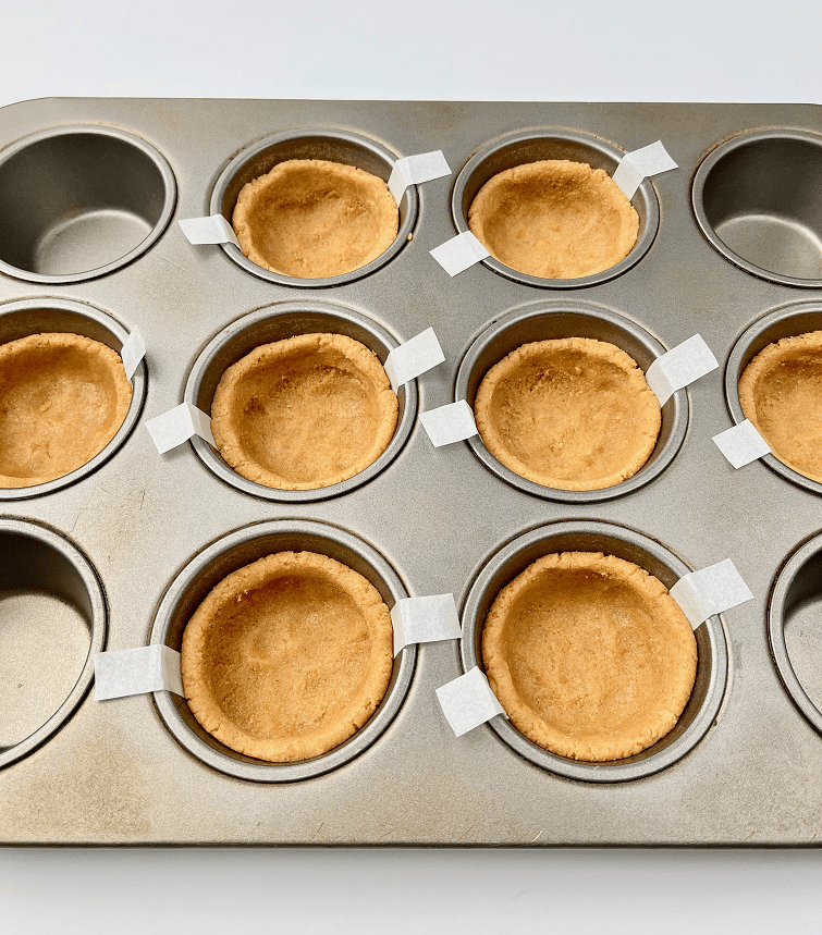 Deep dish smores cookie dough pressed into muffin pan.