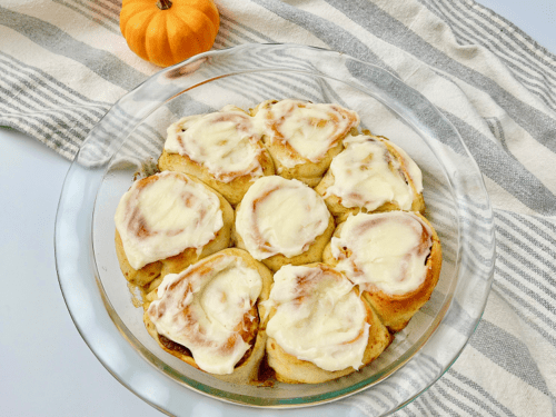 Finished pumpkin pie cinnamon rolls in glass pie plate.