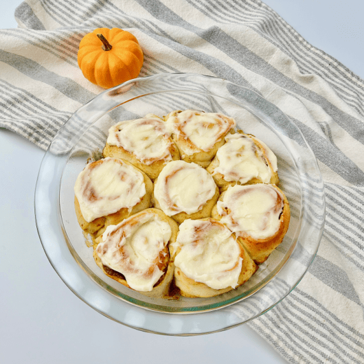 Finished pumpkin pie cinnamon rolls in glass pie plate.