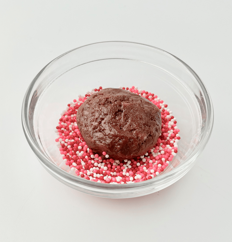 Brownie cookie dough in a bowl of sprinkles.