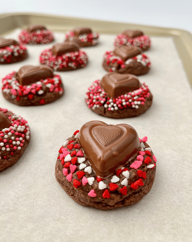 Remove the cookies from the oven and cool for 2-3 minutes before pressing a chocolate heart into the center of each cookie.