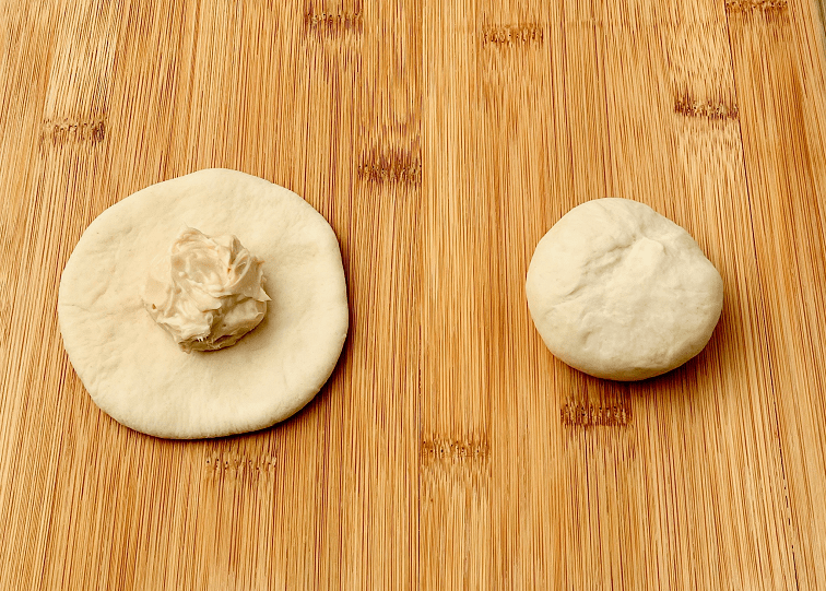 Bagel dough pressed into a circle with a scoop of cream cheese.